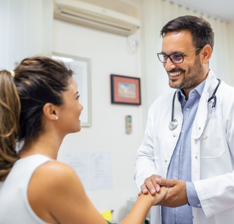 médico sonriente cogiendo la mano de una paciente