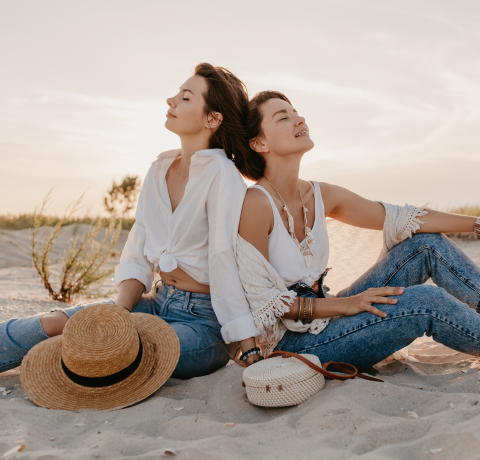 dos mujeres sentadas en la arena disfrutando de la tarde