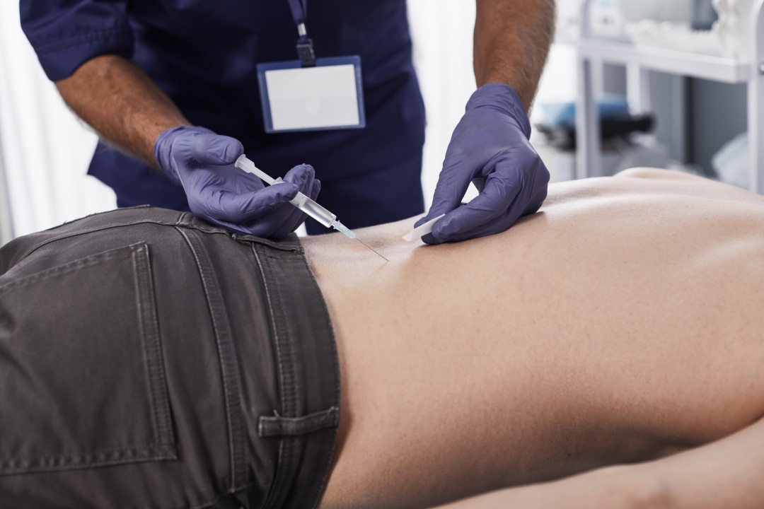 Asesor médico sosteniendo una jeringuilla en las manos y aplicando una inyección a un paciente varón