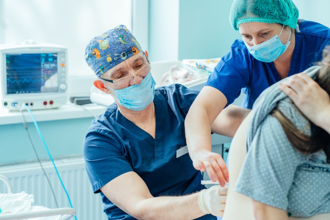 Toma de epidural. Enfermera consolando a una mujer embarazada, el médico administra la Epidural.