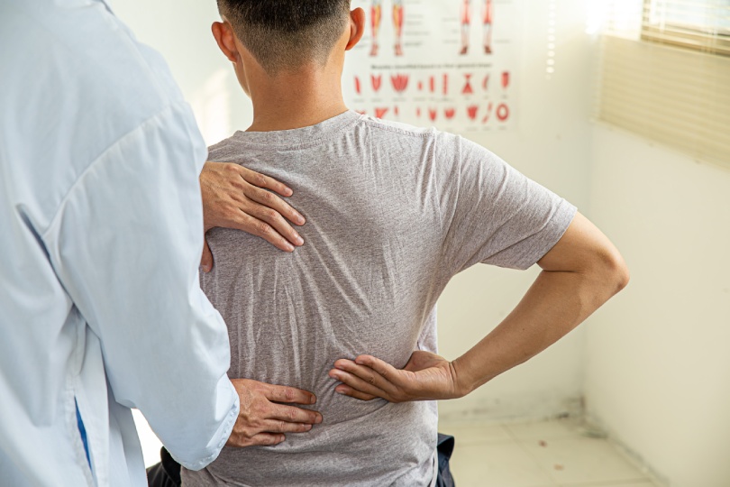 Masculino médico terapeuta de trabajo examinando el tratamiento de la espalda lesionada.paciente con dolor de espalda, el tratamiento, el médico, el masaje para el alivio del dolor de espalda síndrome de la oficina.