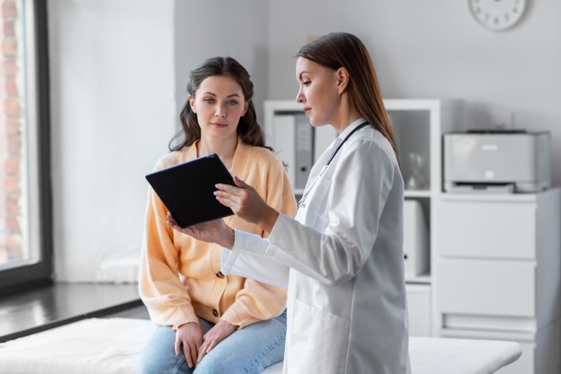 medicine, healthcare and people concept - female doctor with tablet pc computer talking to woman patient at hospital