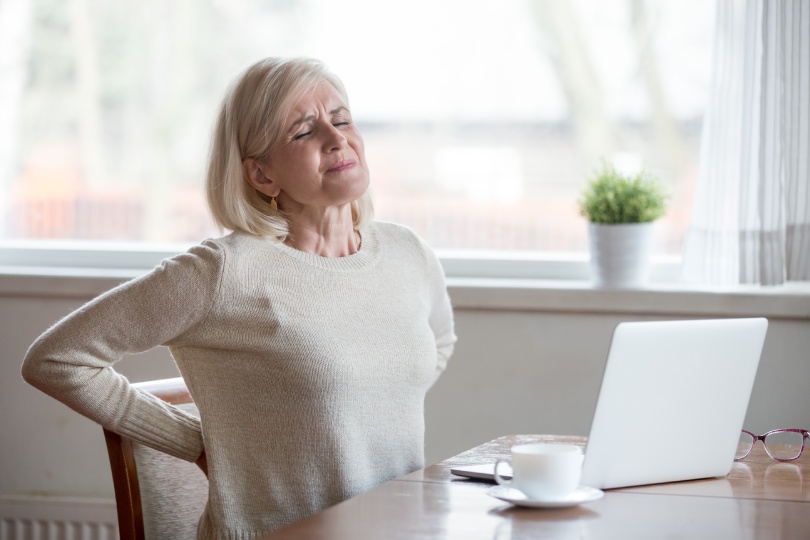 Upset mature middle aged woman feels back pain massaging aching muscles, sad senior older lady suffers from low-back lumbar pain sitting in incorrect sedentary posture, backache radiculitis concept